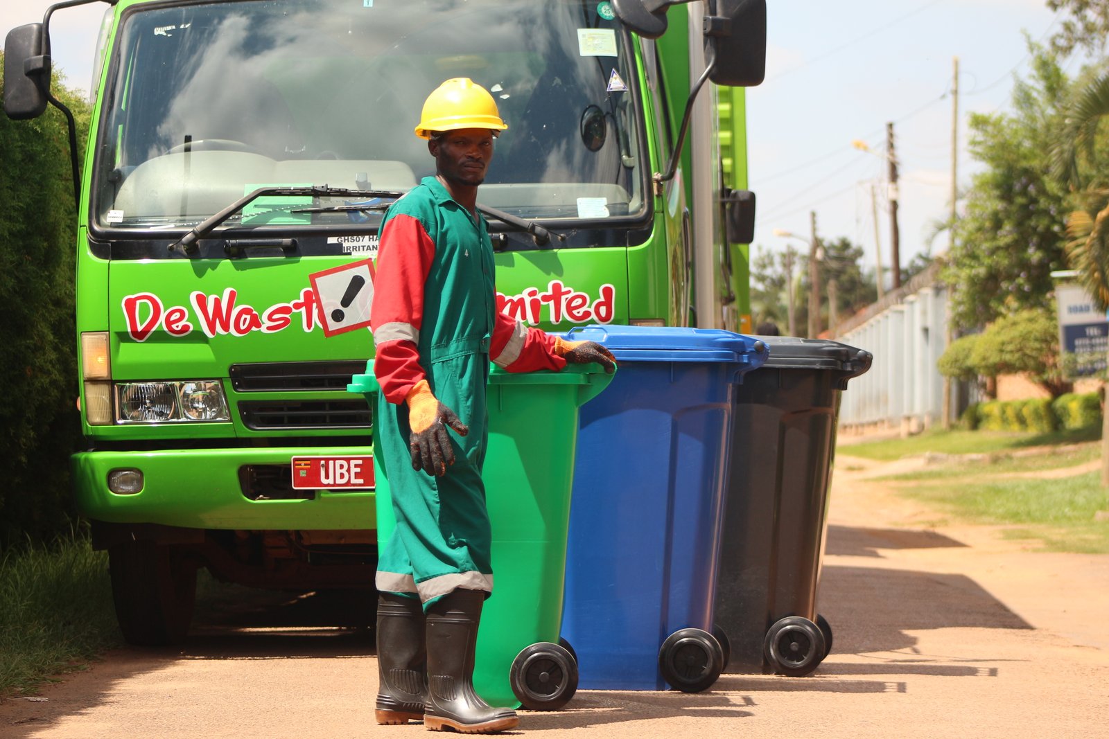 De Waste uniformed worker with collection truck and bins